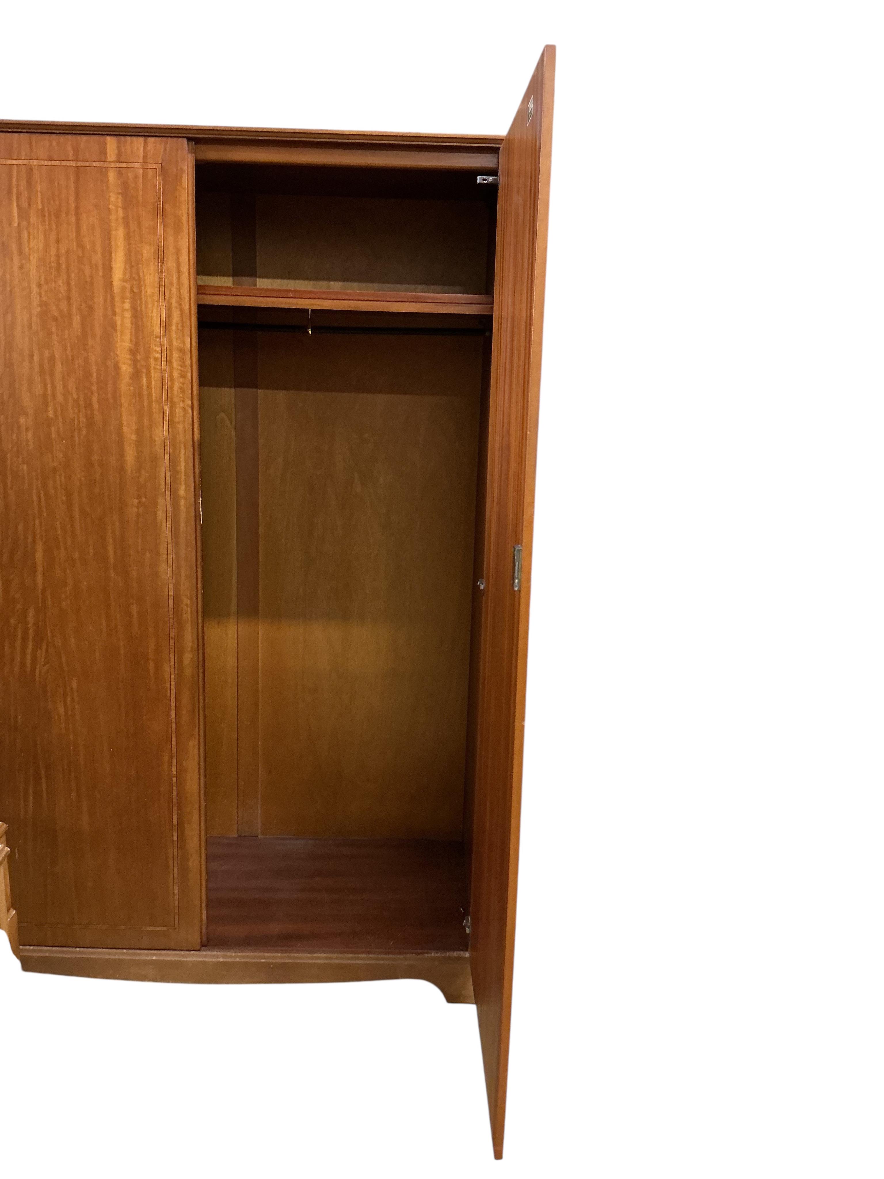 A mid century teak Beithcraft furniture bedroom suite, comprising a two door wardrobe, a kneehole dressing table with stool, headboard and a five drawer chest